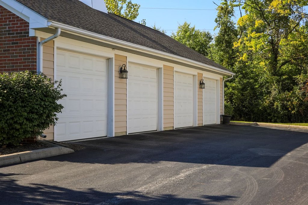 a white garage with three white doors on a brick building