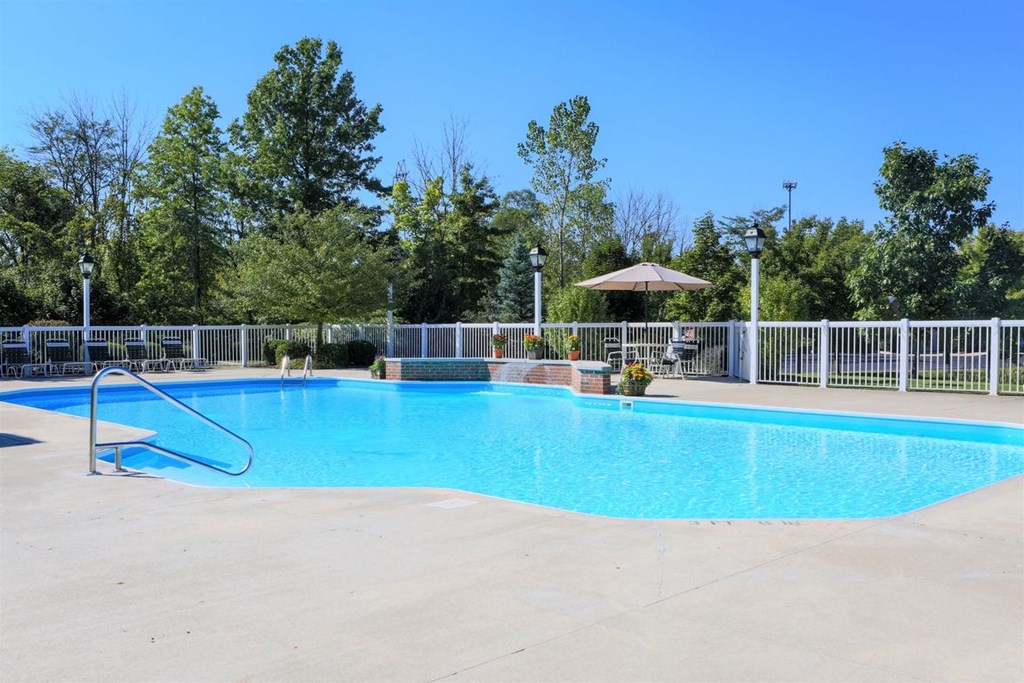a swimming pool with a fence around it and trees in the background