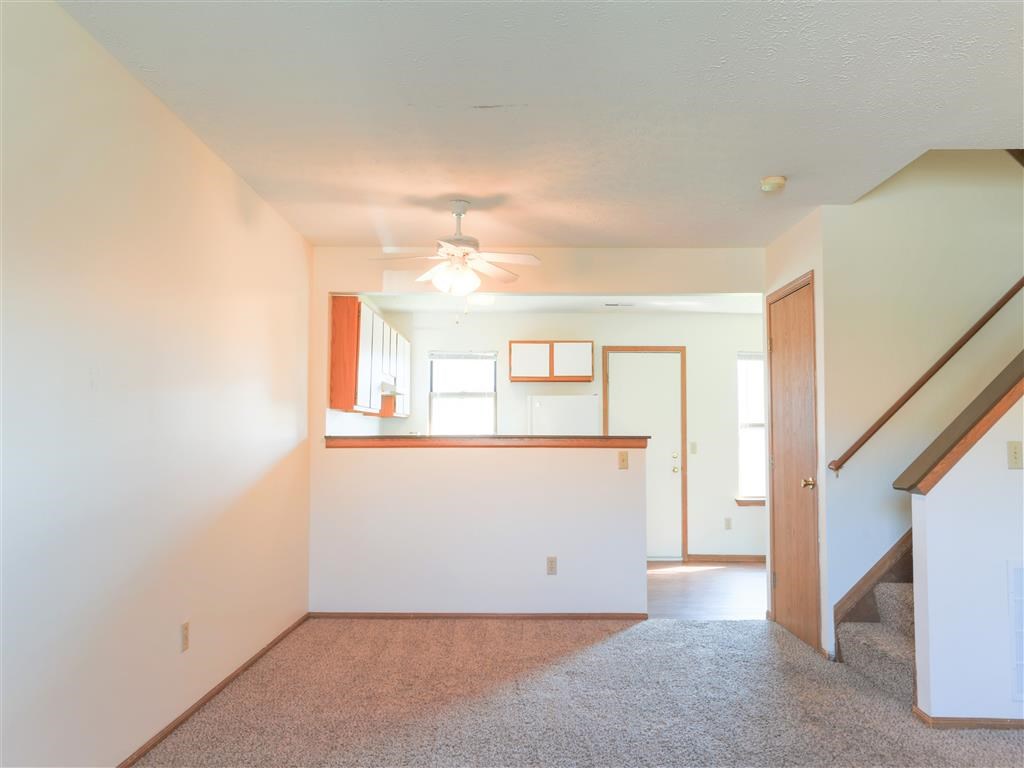 an empty living room and kitchen with a ceiling fan