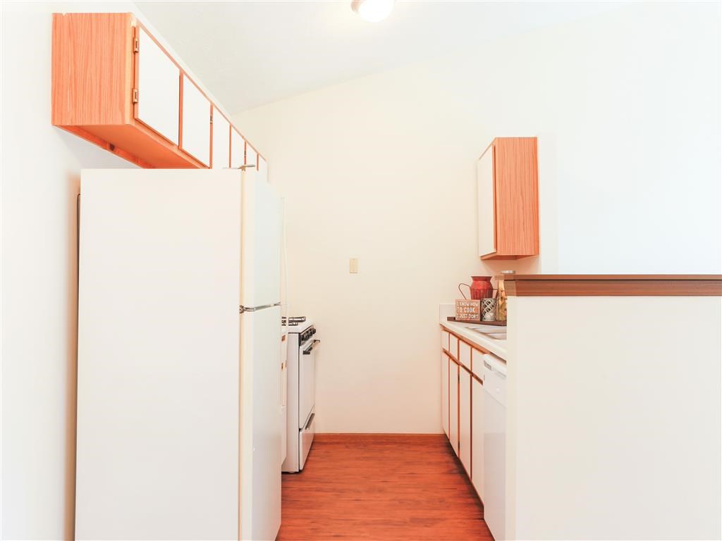 a kitchen with white appliances and a wood floor