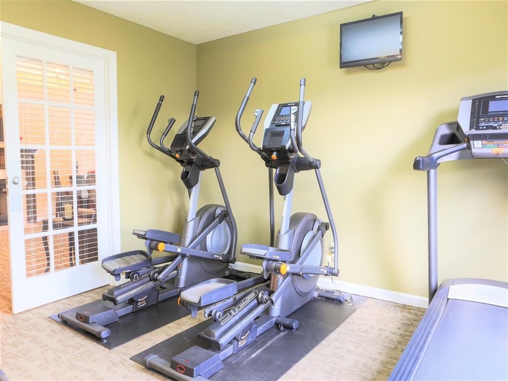 a gym with several machines and a television