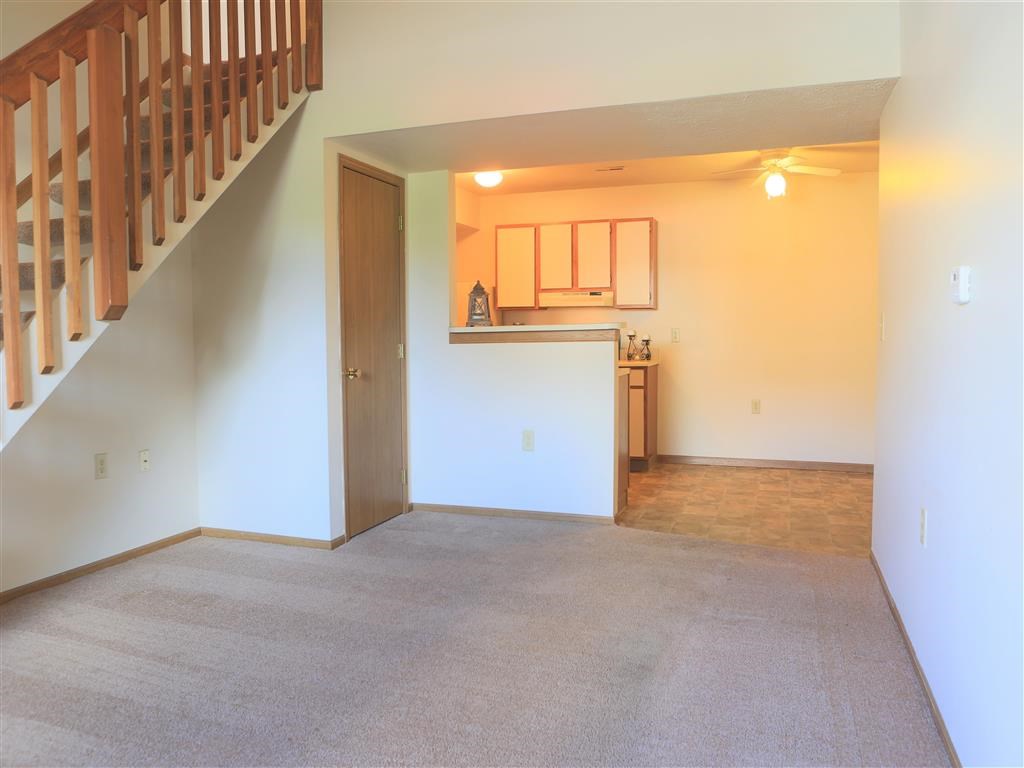 an empty living room and kitchen with a staircase