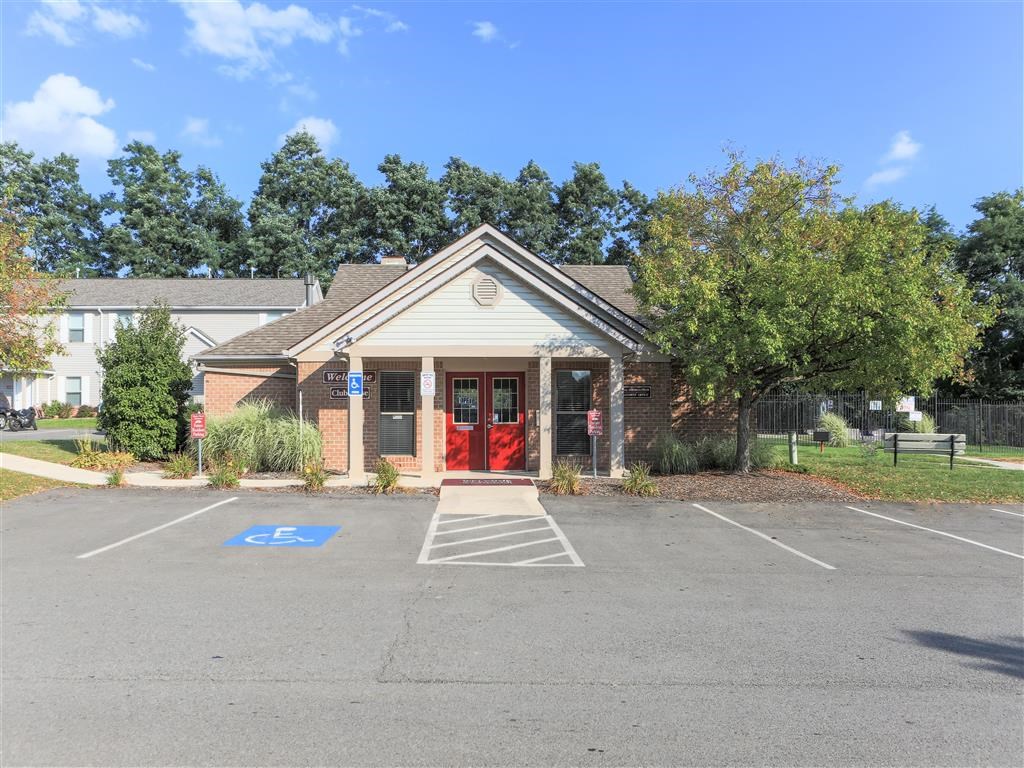the front of a building with a parking lot and a red door