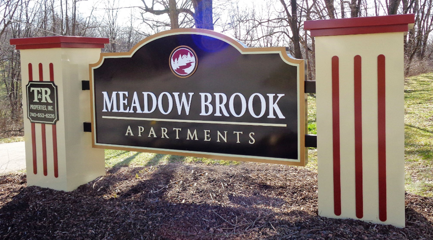 the sign for meadow brook apartments at the entrance to the park