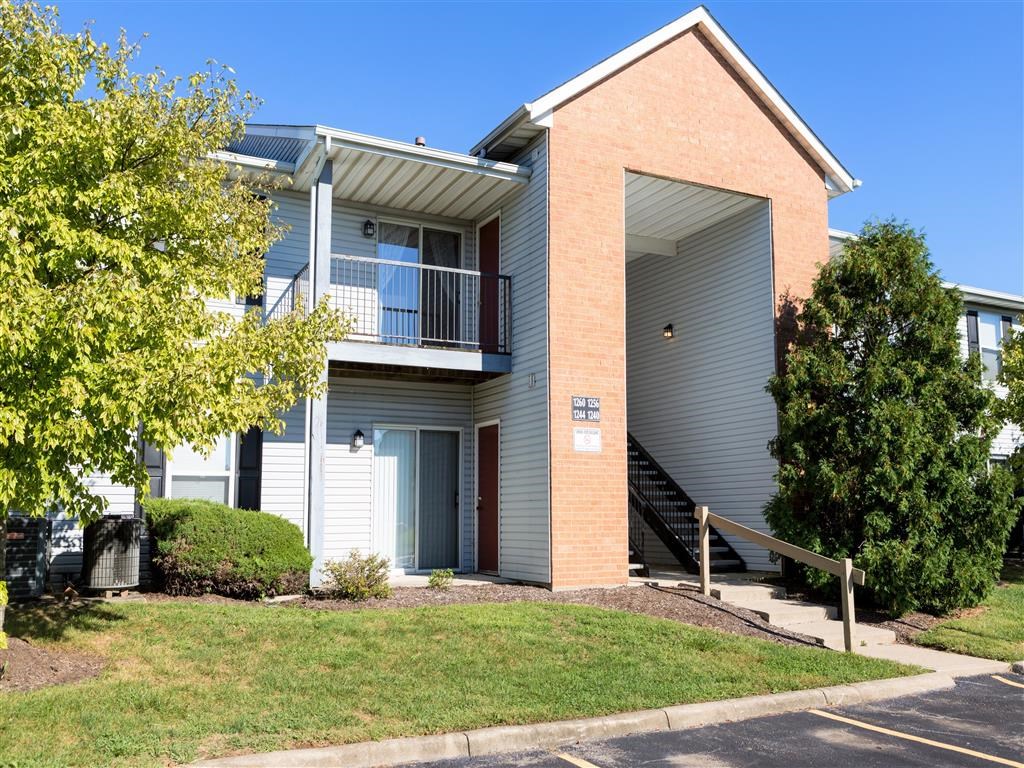 the front of an apartment building with a porch and stairs