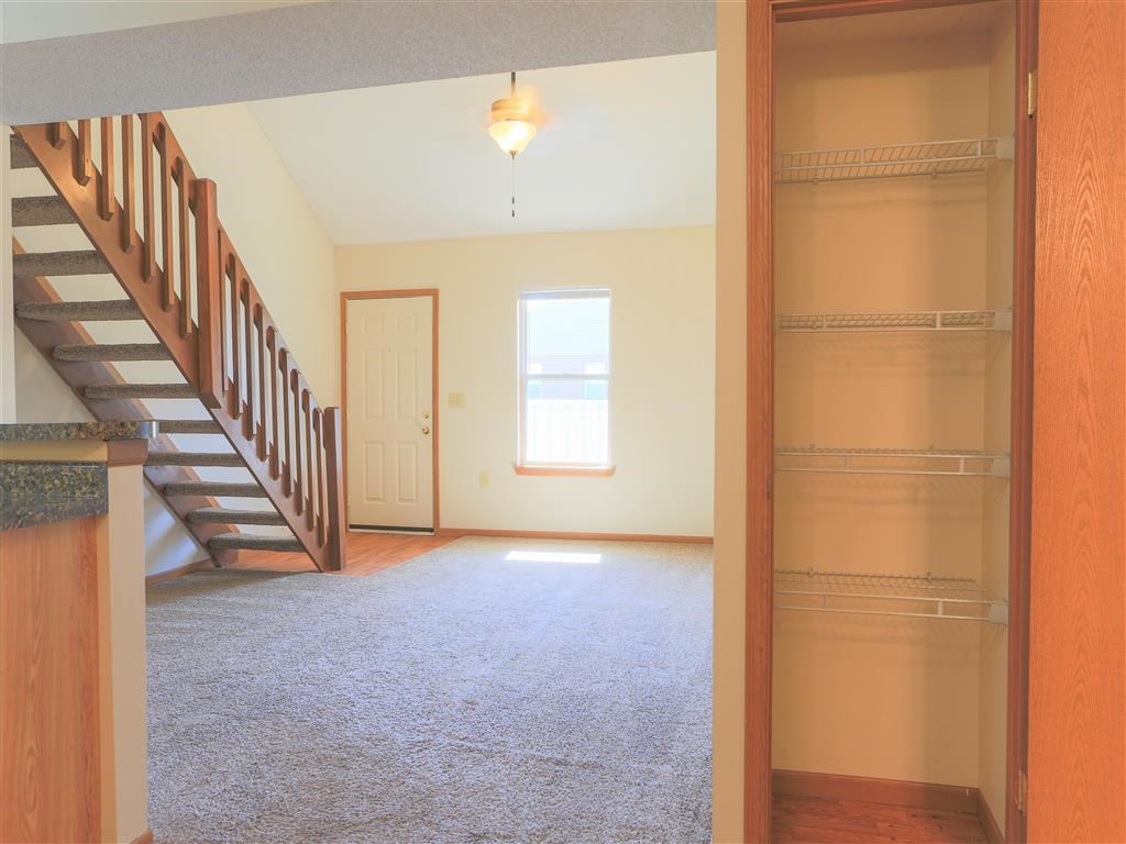 an empty living room with a staircase and a door
