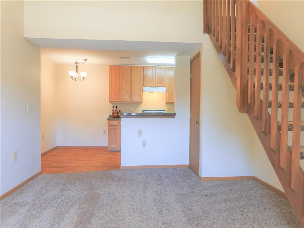 an empty living room with a staircase and a kitchen