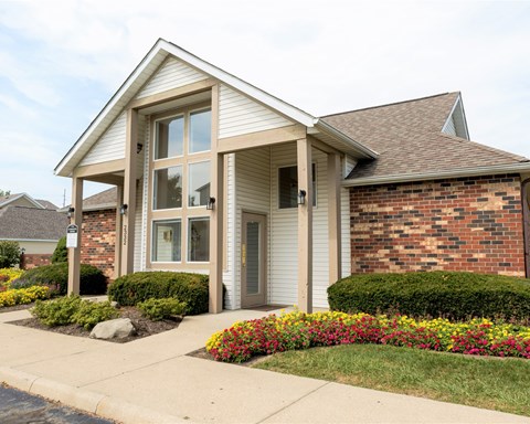 a small brick house with a sidewalk in front of it