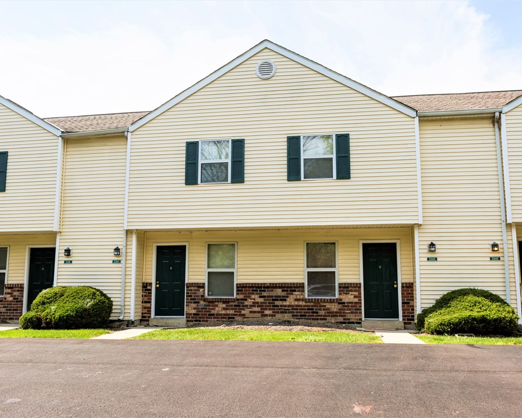 the front of a white house with black doors