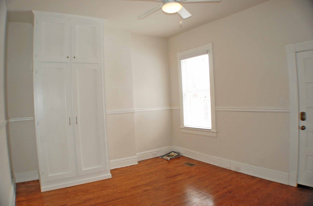 an empty room with white walls and a window and a wooden floor