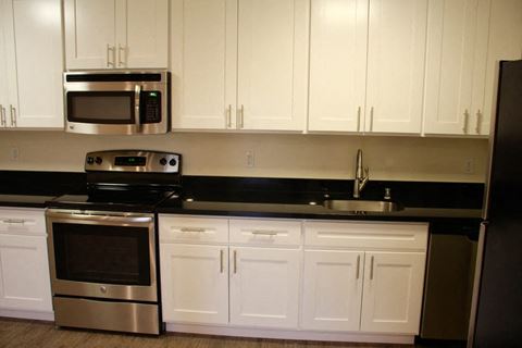 a kitchen with white cabinets and black counter tops