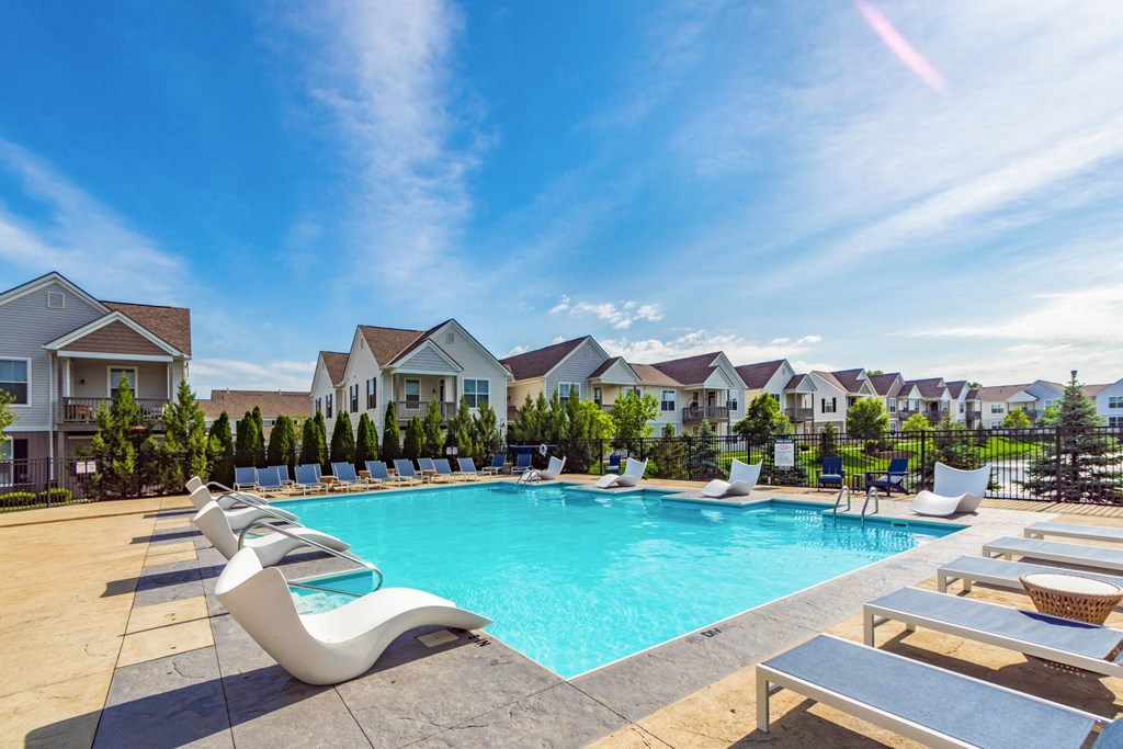 a swimming pool with lounge chairs and houses in the background