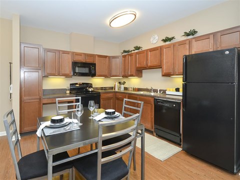 A kitchen with a black refrigerator and wooden cabinets.