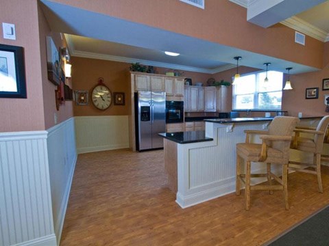 A kitchen with wooden floors and a black refrigerator.