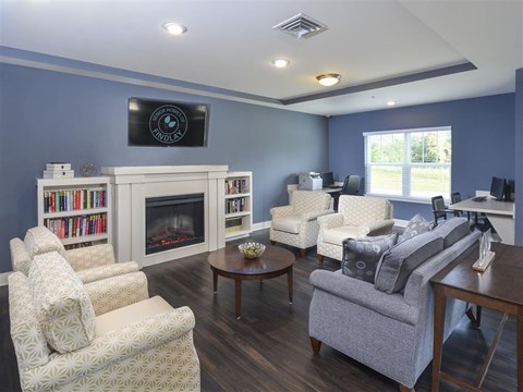 A living room with a fireplace and a television mounted above it.