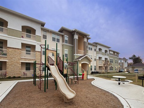 A playground with a slide in front of apartment buildings.