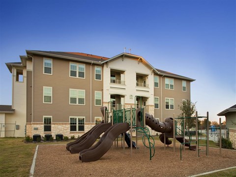 A playground with a slide in front of a large apartment building.