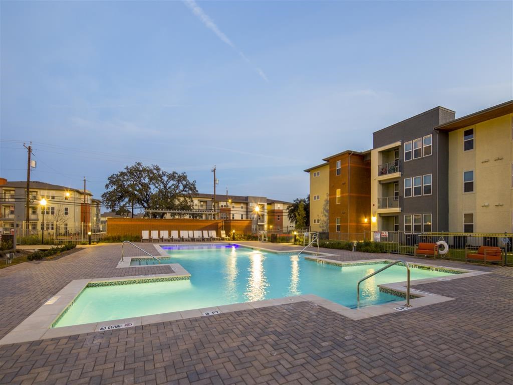 a swimming pool in front of an apartment building at dusk