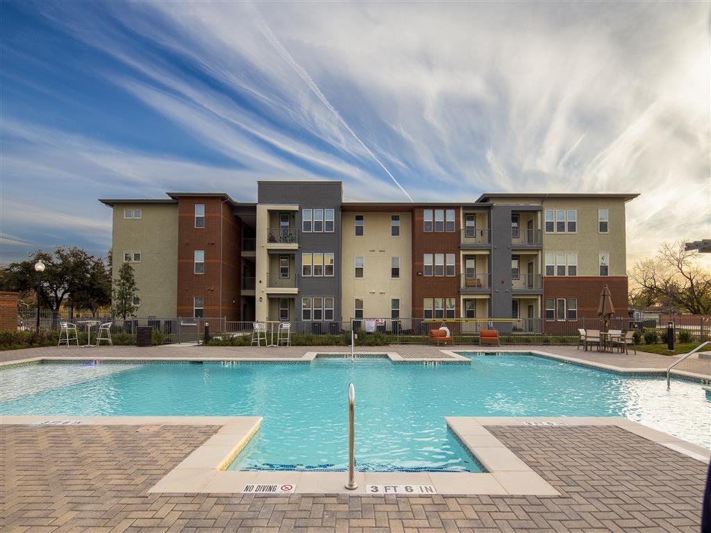 a swimming pool with an apartment building in the background