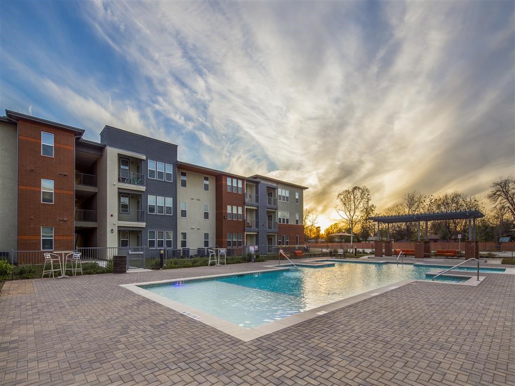 an apartment building with a pool at sunset