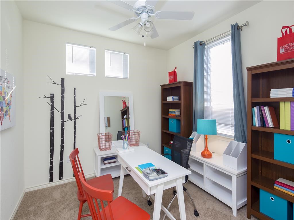a home office with a white desk and a ceiling fan