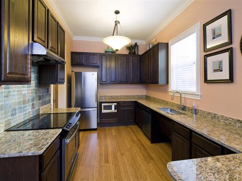 A kitchen with dark wood cabinets and granite countertops.