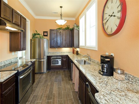 A kitchen with a refrigerator, oven, microwave, and sink.