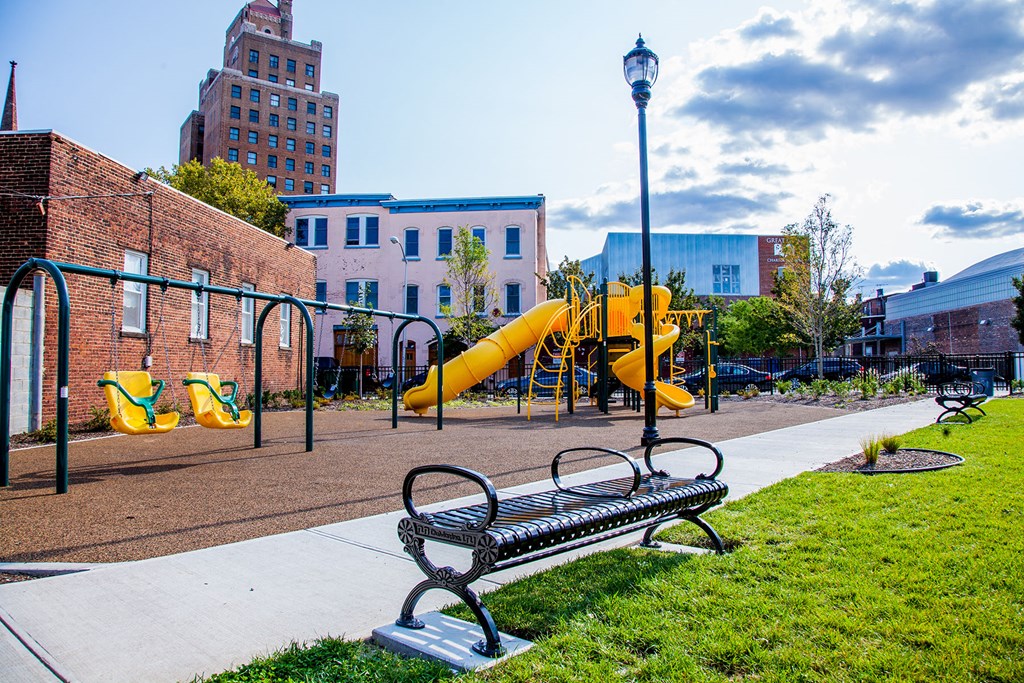 a playground with a bench and slides in a park