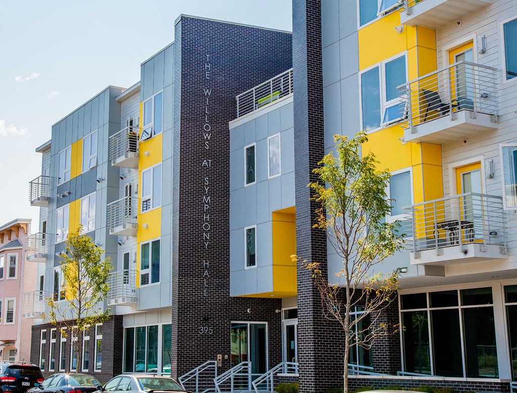 a new apartment building with yellow and gray facade and cars parked outside