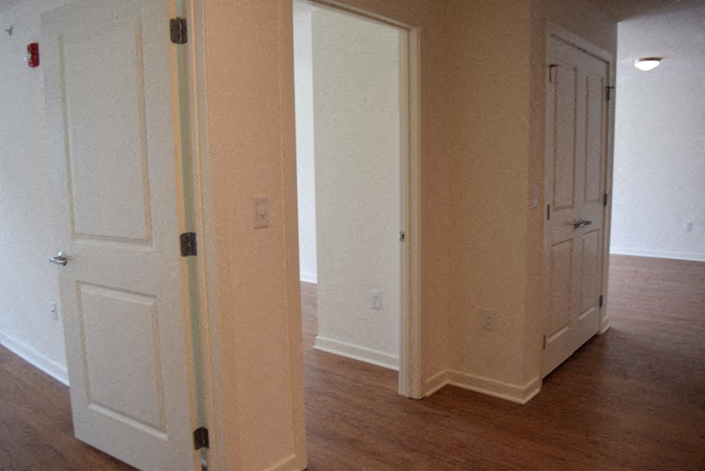 an empty room with white doors and a wood floor