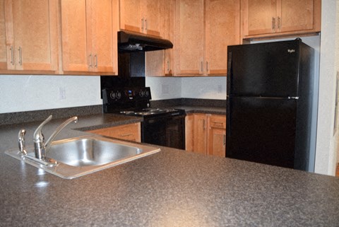 a kitchen with a sink and a black refrigerator