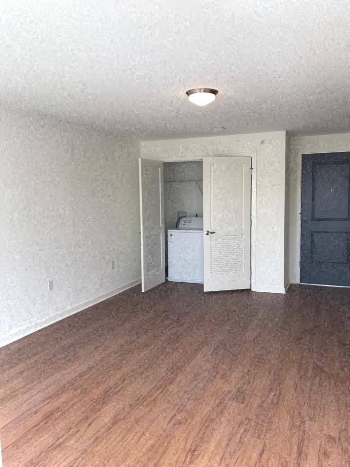 an empty living room with wood floors and a blue door