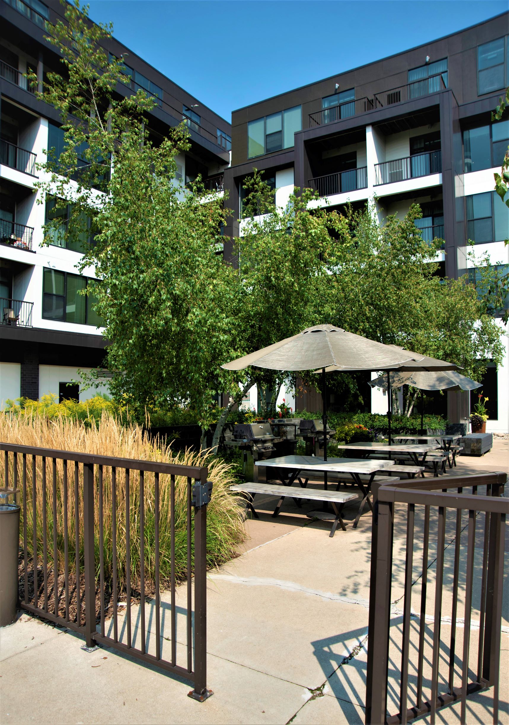 an outdoor area with a picnic table and umbrella in front of an apartment building