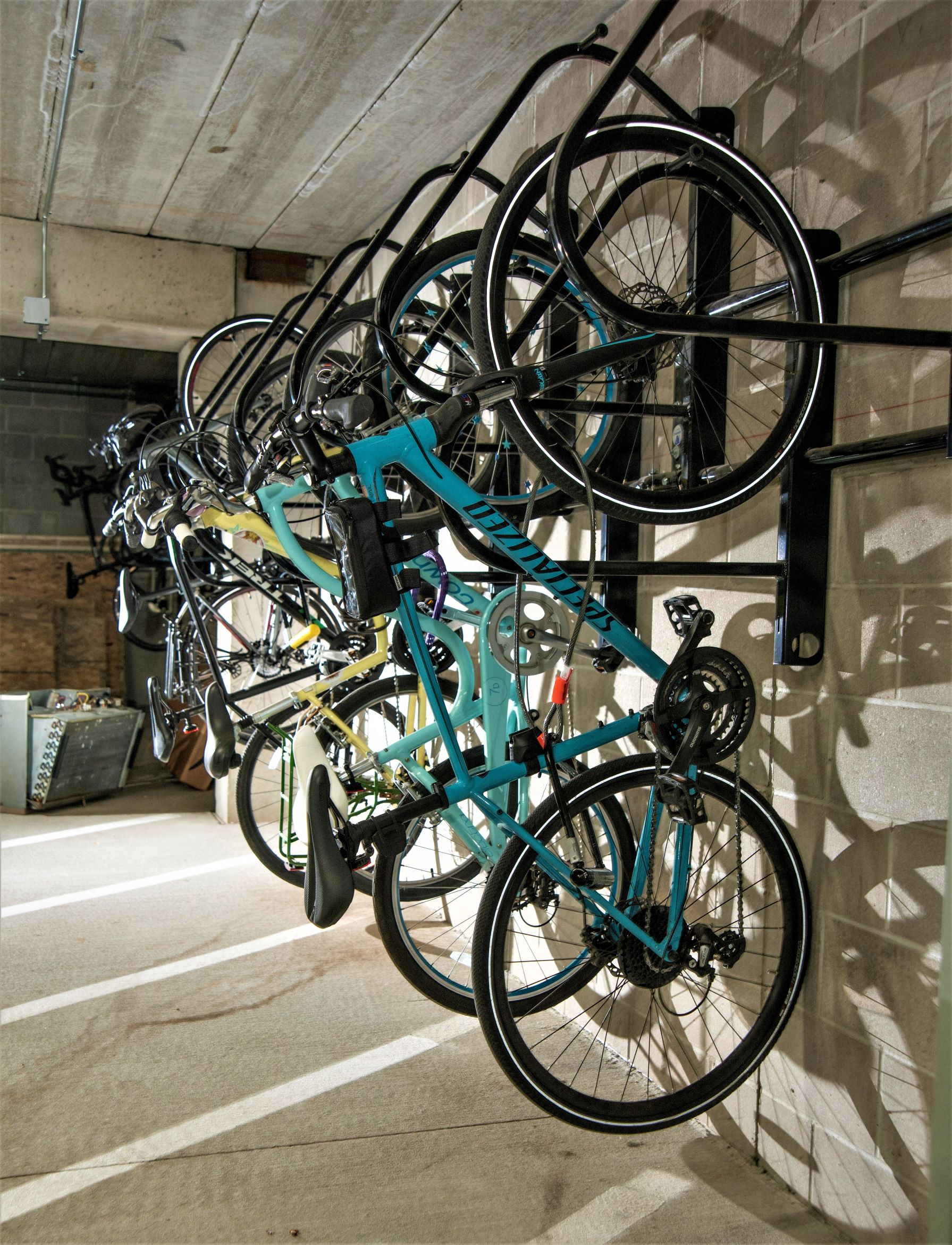 a row of bikes hanging on a wall in a parking garage
