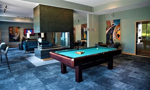 a pool table in the lobby of a club with a fireplace