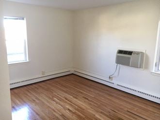 an empty room with wood floors and an air conditioner