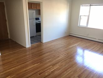 an empty living room with wood floors and a kitchen