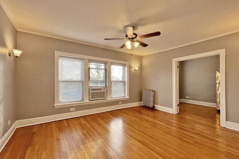 A room with a ceiling fan and hardwood floors.