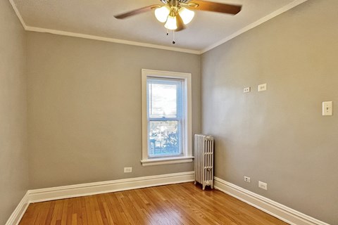 A room with a ceiling fan and a window with blinds.