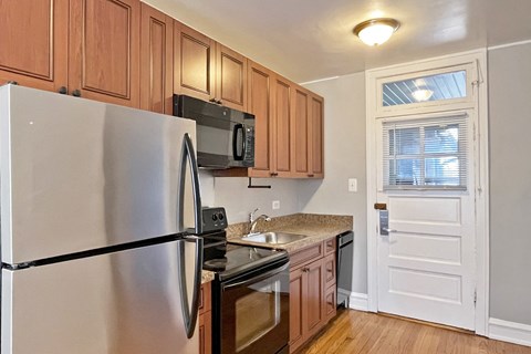 A kitchen with a refrigerator, microwave, oven, and sink.