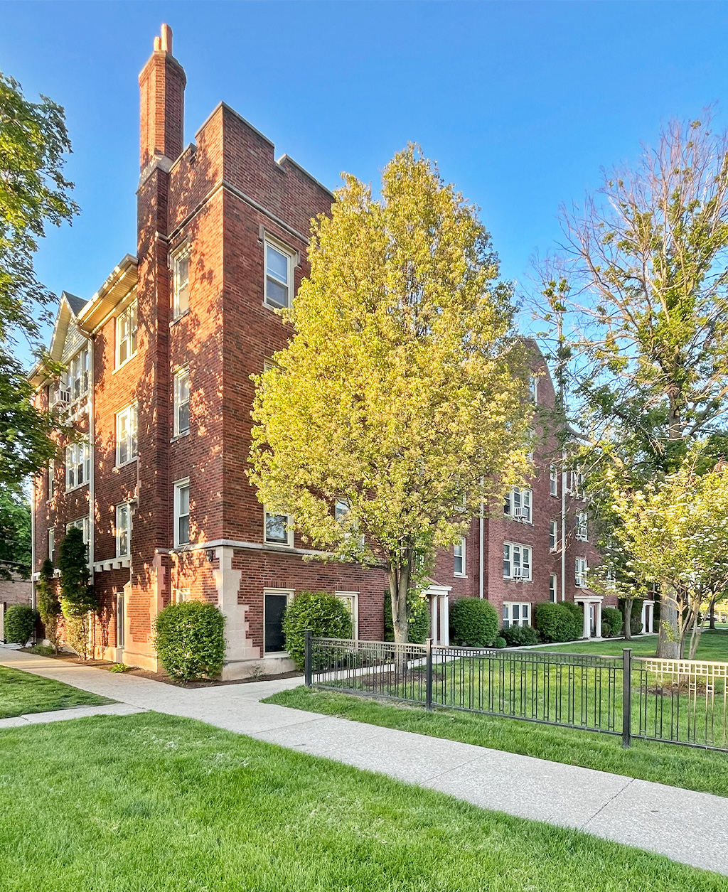 A red brick building with a black fence in front.