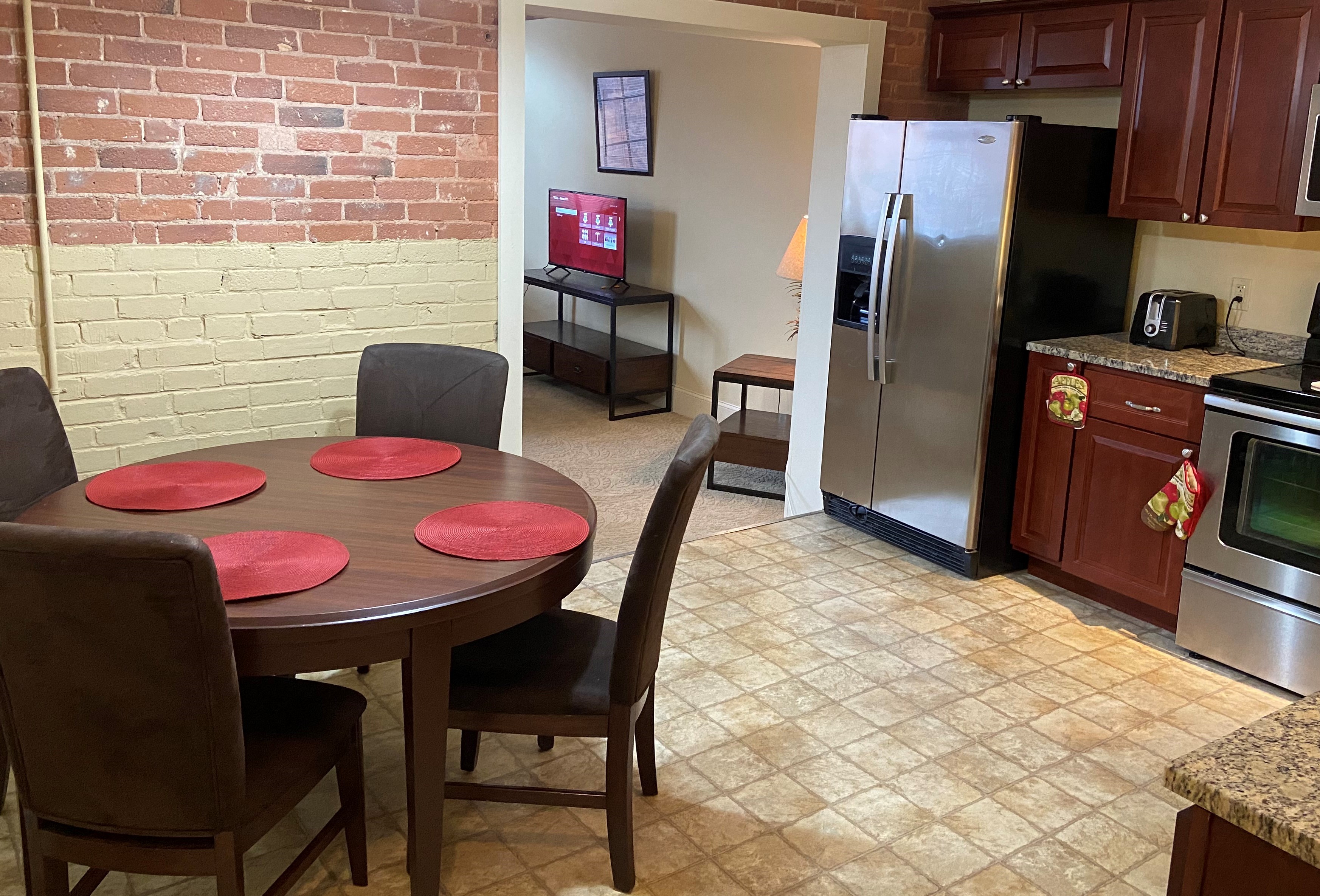 a dining room with a table and a kitchen with a refrigerator