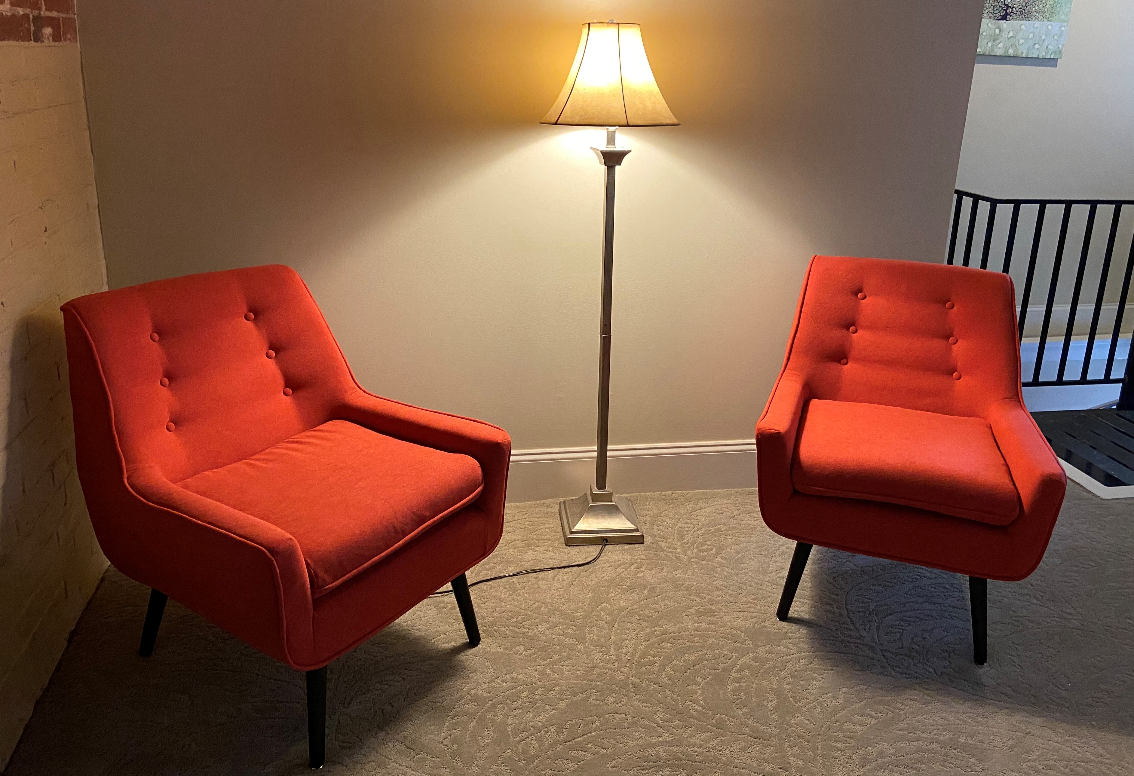 two orange chairs in a living room with a lamp and a chair
