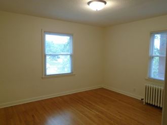 an empty room with a wood floor and two windows