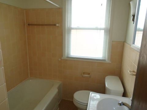 a bathroom with a toilet and a tub and a window