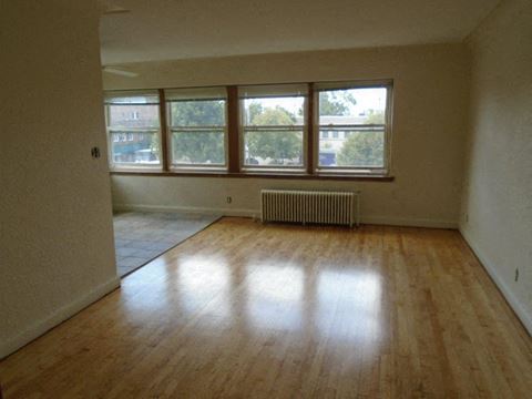 an empty living room with a wood floor and windows