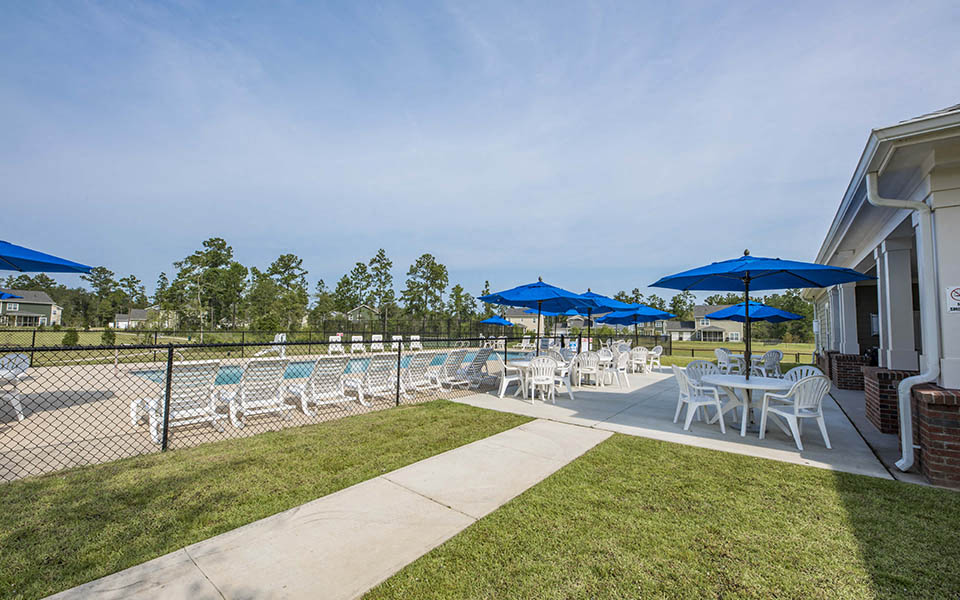a patio with chairs and umbrellas and a pool
