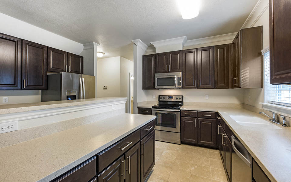 a large kitchen with dark wood cabinets and white counter tops
