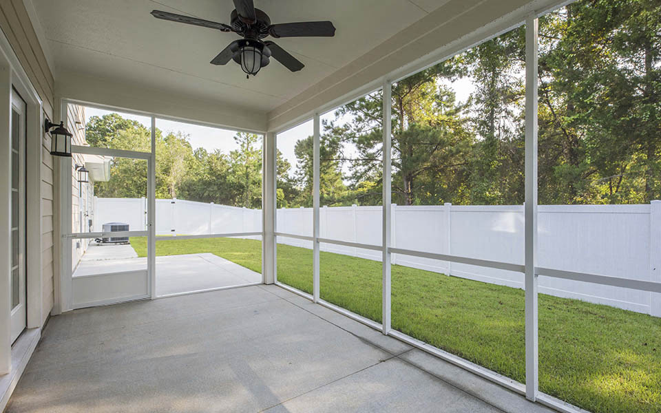 a covered porch with a ceiling fan and glass doors