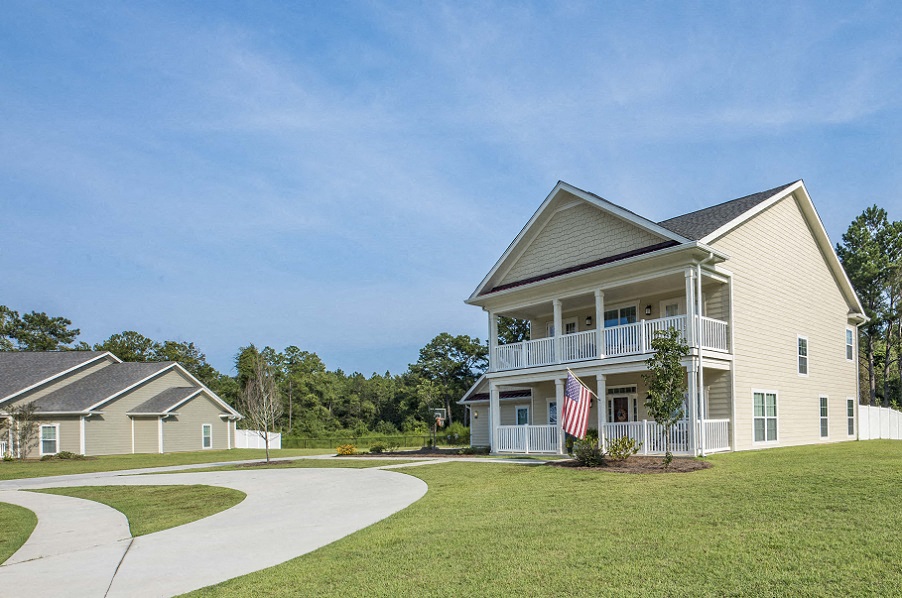 a house with an flag on the porch and a winding driveway